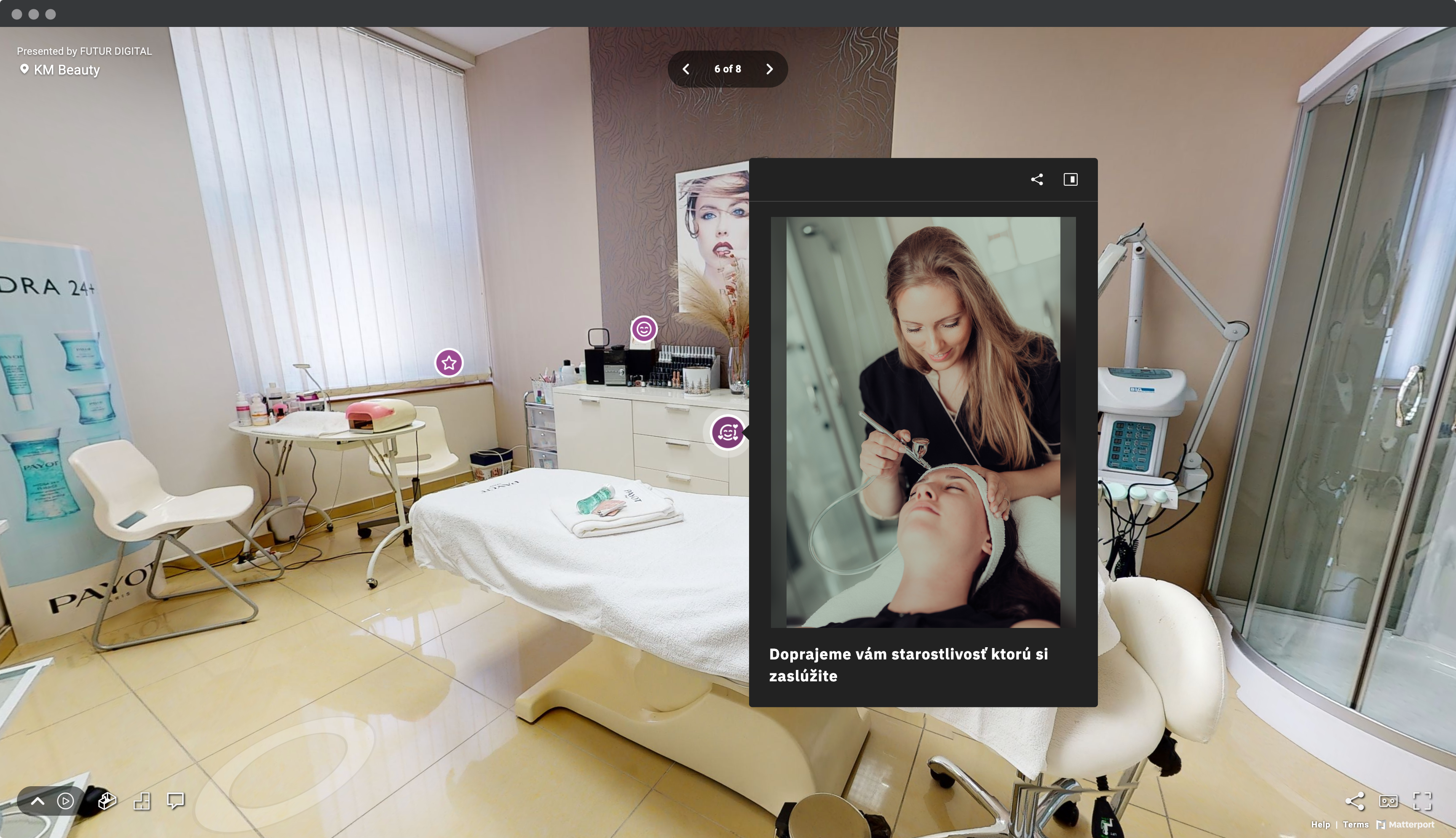 Screenshot okna prehliadača s virtuálnou prehliadkou beauty salóna KM Beauty so záberom na kozmetickú miestnosť s kozmetickým stolom, stoličkami a označneným bodom záujmu - fotka kozmetičky a klientky počas procedúry.